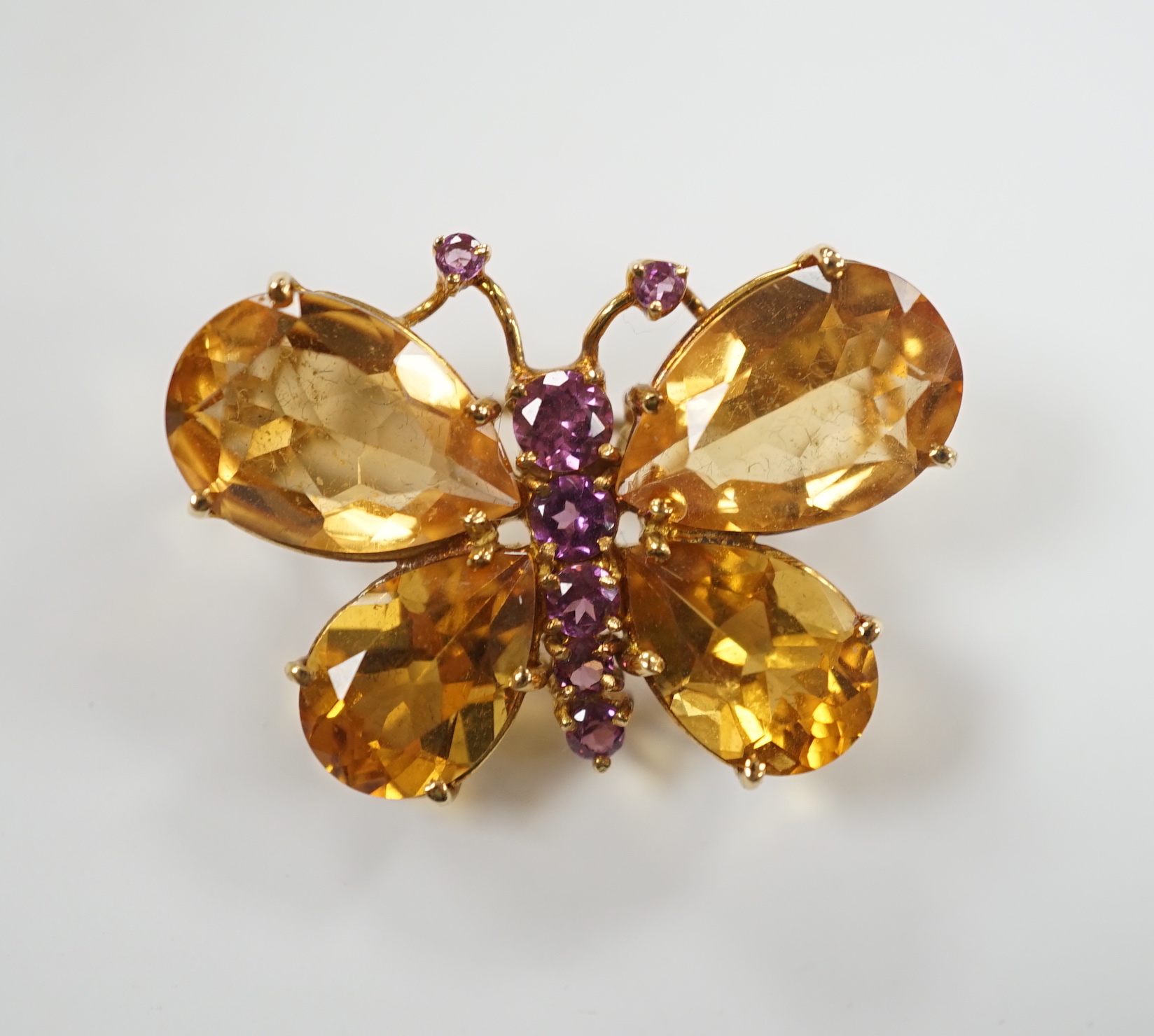 A modern Italian 750 yellow metal, four stone citrine and graduated seven stone pink sapphire set butterfly brooch, width 32mm, gross weight 8.1 grams.